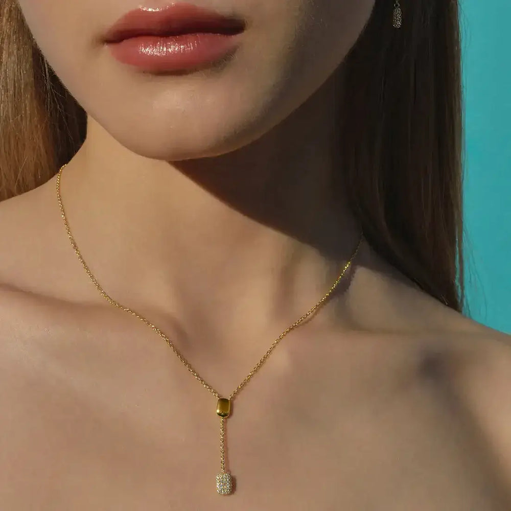 Модел носи позлатено колие от сребро с правоъгълен медальон и бели цирконии от колекция Heritiere