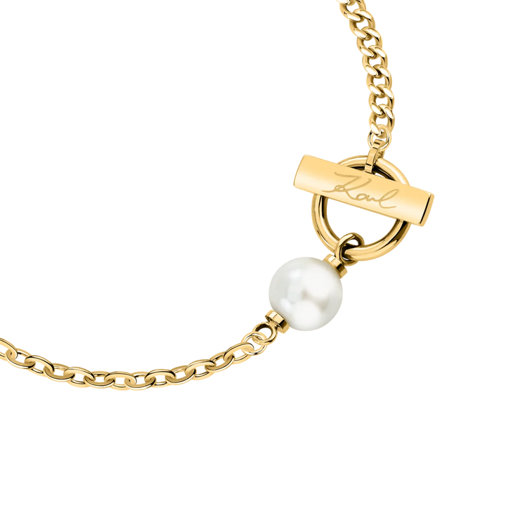 Детайлен кадър на дамска гривна Karl Lagerfeld със златист елемент с подпис Karl и бяла перла – KLAYR13